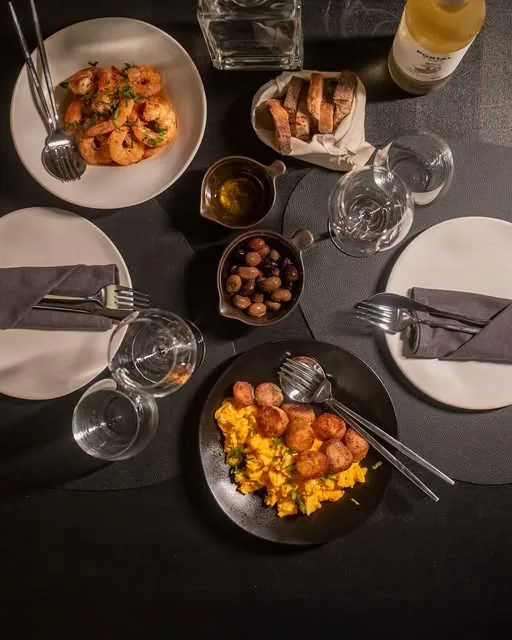 Mesa posta para dois, com camarões, pão, azeitonas e vinho